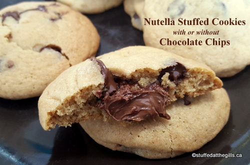 The picture shows a plate of the Nutella Stuffed Cookies with one broken open showing the Nutella oozing out.