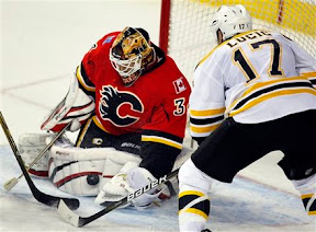 Mikka Kiprusoff making a save and Milan Lucic looking for a rebound