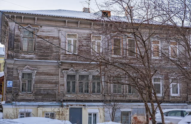 Деревянный дом с широким окном, резными наличниками и консолями под крышей