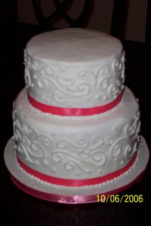 Two tier round white wedding cake with red ribbons