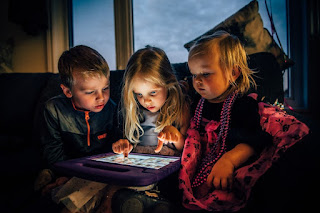 Three siblings looking at a tablet computer