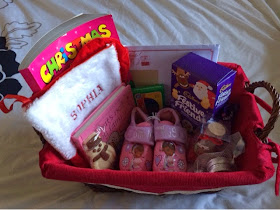 contents of a Christmas Eve basket, sweets, slippers and colouring book