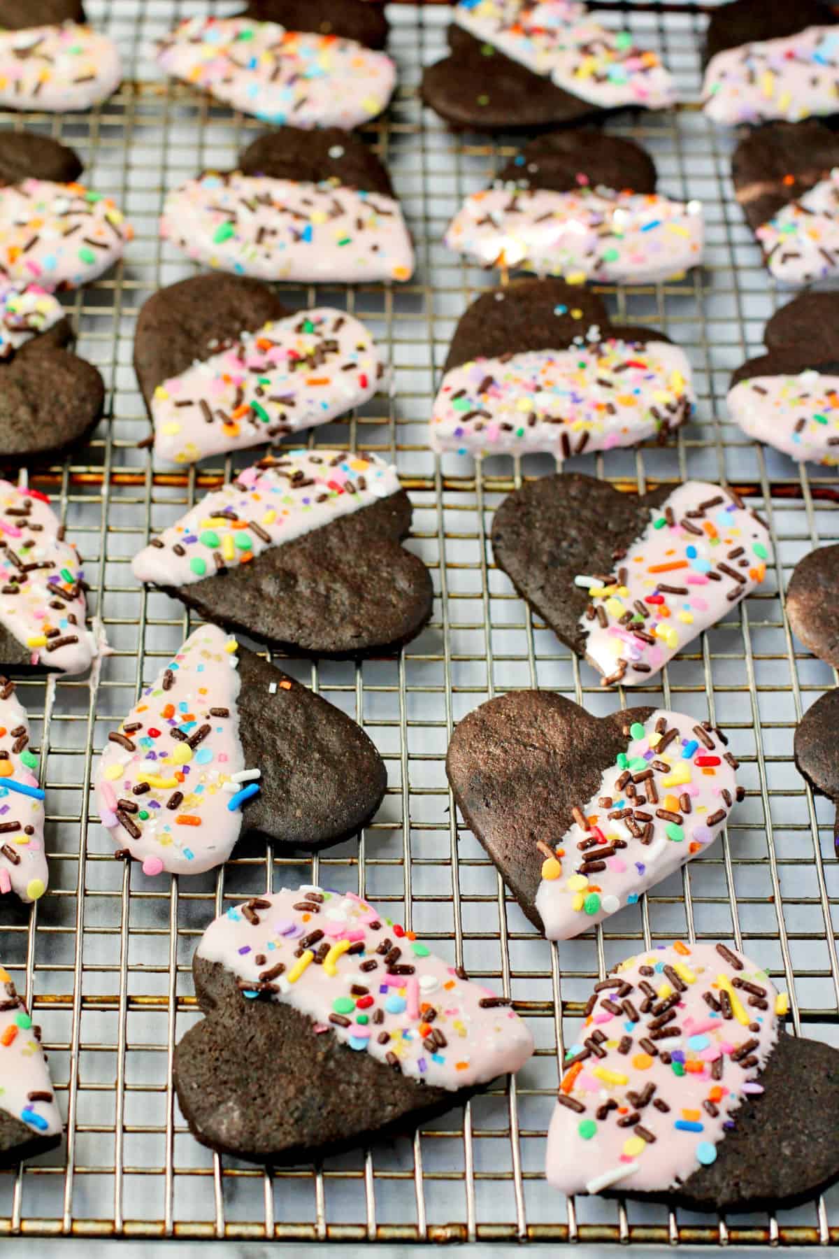 Chocolate Valentine Sugar Cookies dipped and sprinkled and on a rack.