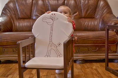 a small girl is playing with the chair in the living-room