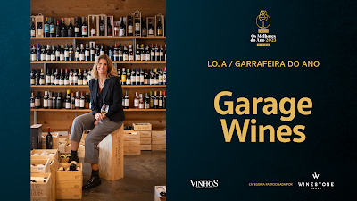 mulher sentada em caixas de vinhos com prateleira de vinhos ao fundo com o texto: Garrafira do Ano Garage Wines Matosinhos