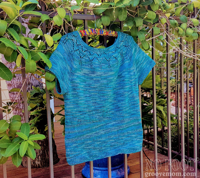 completed sweater hangs on the fence with the stephanotis vine