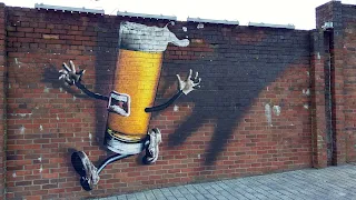 Street Art on a brick wall. A personified pint of lager with arms, legs, and a mouth. The beer has a shadowy hand coming for it and appears to be running away scared.