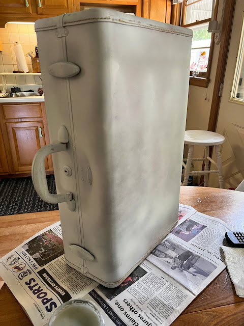 Photo of an old hard plastic suitcase primed with spray primer.