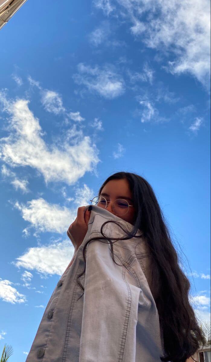 Foto tumblr chica sin mostrar la cara con el cielo y nubes de fondo