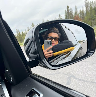 Charles Melton clicking a selfie while sitting inside the car using the side mirror