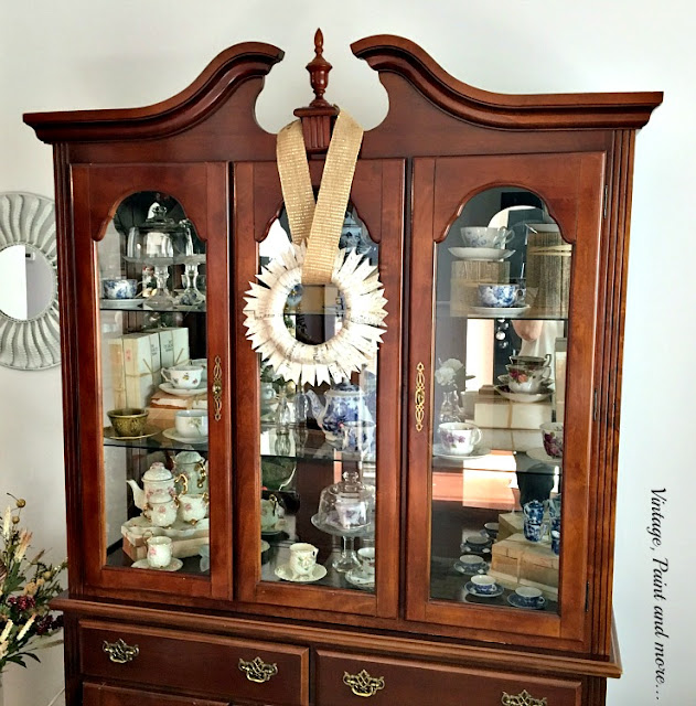 paper wreath with burlap ribbon on china hutch