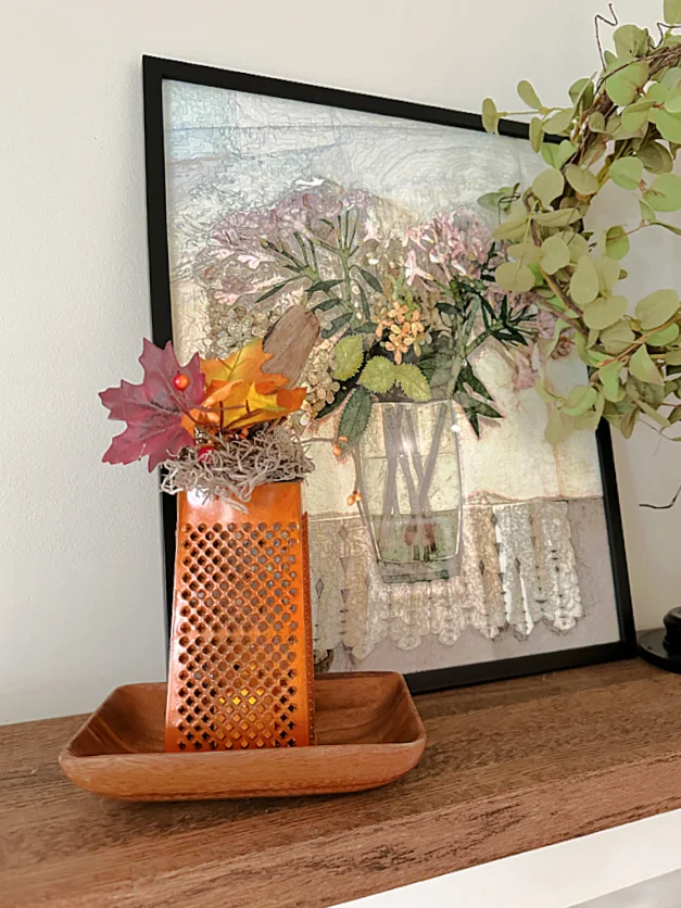 cheese grater lantern and painting on mantel