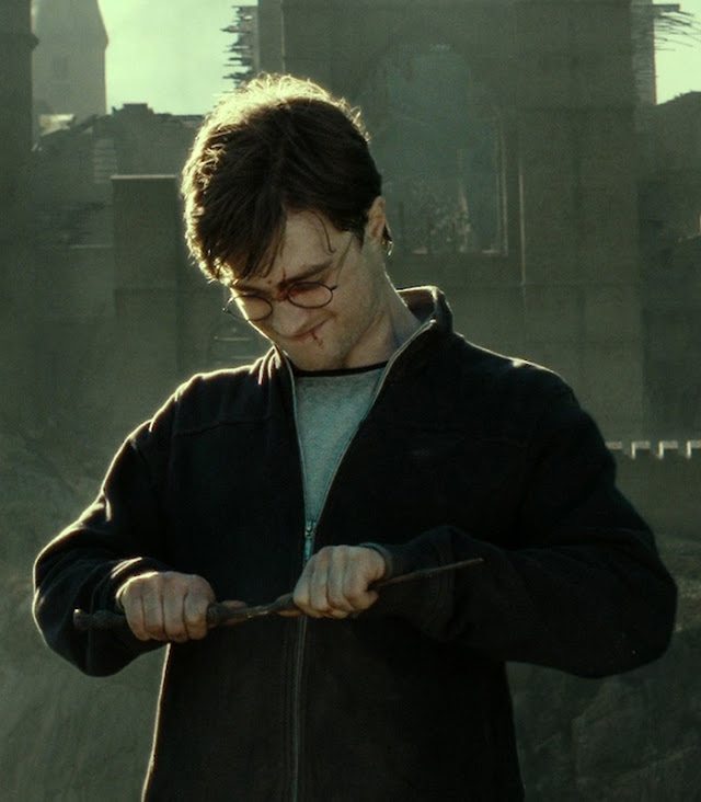 Harry Potter is holding a wand and trying to break it.