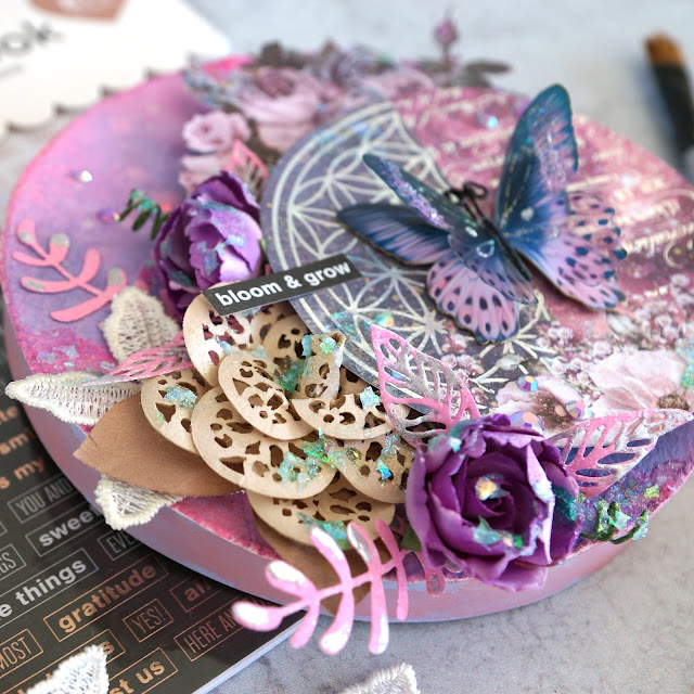 Prima Moon Child, Pretty Pale and Soprano flowers and lace trim; Tim Holtz Distress Spray Oxide and Stain in kitsch flamingo and dusty concord and Funky Floral dies; Scrapbook.com stickers and smart glue adhesives; Pinkfresh Essentials jewels