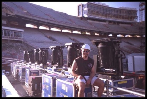 Tom Bowser sitting on a road case during setup for the Rolling Stones Voodoo Lounge Tour at Camp Randall Stadium in Madison, WI