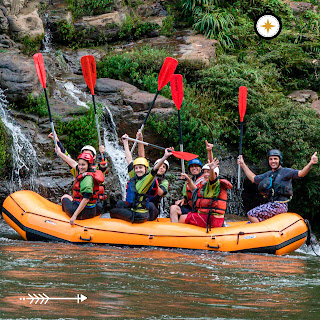 Un grupo de turistas se divierte y alza sus remos mientras hacen rafting, capturando un momento emocionante para la foto.