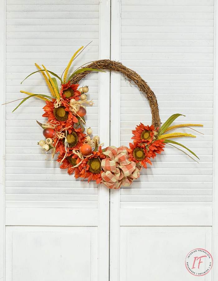 An easy orange sunflower fall wreath DIY idea in bright traditional autumn colors and a recycled grapevine wreath, a budget-friendly fall door wreath.