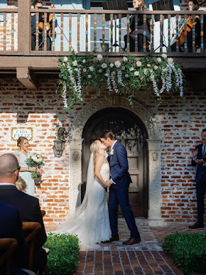bride and groom kissing at casa feliz under flowers during ceremony