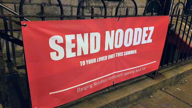 Red street banner #SendNoodez advertising new restaurant