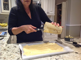 woman spreading plantain batter on parchment paper on a cookie sheet