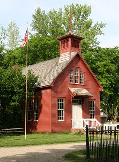 Early American red Brick Schoolhouse With White Door and american Flag Pole