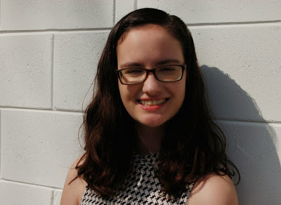 A photo of the author in front of a white wall.