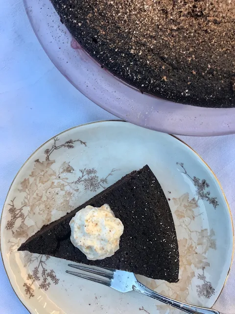 Serving plate with a slice of flourless black bean chocolate cake next to the finished cake.