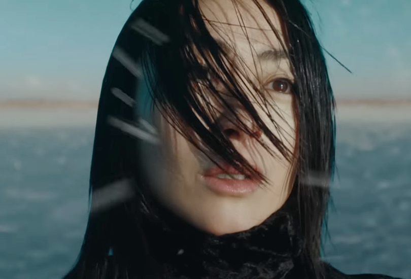 A screenshot of Hikaru Utada in the music video for "Nani Iro Demo Nai Hana". Featuring a close-up of Hikaru’s face as flakes of snow blow in the wind. The music video was shot on a frozen lake in Hokkaido, Japan.