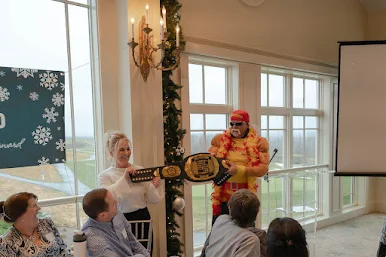 Man dressed in Hulk Hogan costume holding up JMC title belt with woman