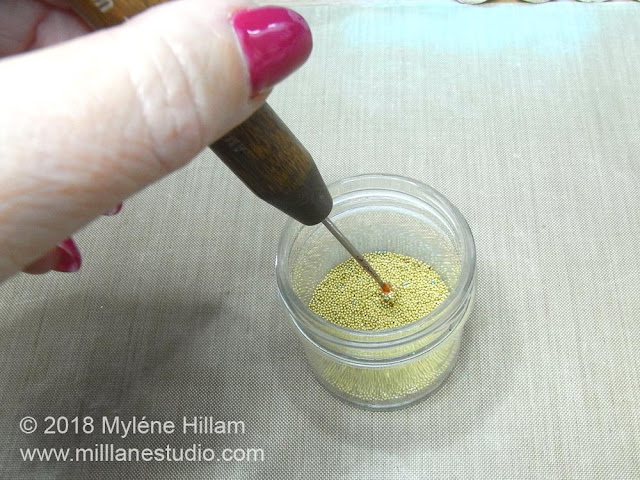 Dipping the point of the needle tool into the jar of gold bead caviar to coat the resin.