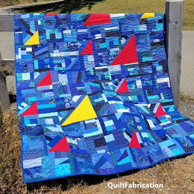 blue scrap quilt with yellow and red triangles for sails