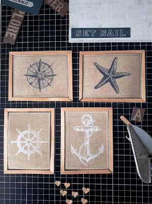 Cutting mat with miniature sailing-themed pictures with wooden frame pieces arranged around them. To one side is a pile of coffee stirrer pieces, and to the other side is an Easy cutter.