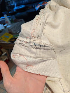 a hand holds the waistband, opened at the seam to see the interior. more basting is visible in the seam allowance.