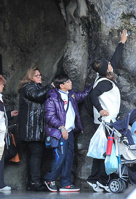 Tocando a pedra abençoada da gruta