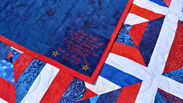 Red, white, and blue batik string quilt with embroidered label