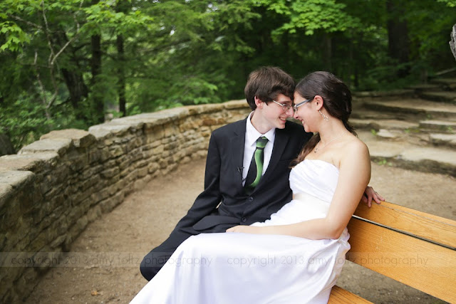 Young couple cuddling on bench on their wedding day