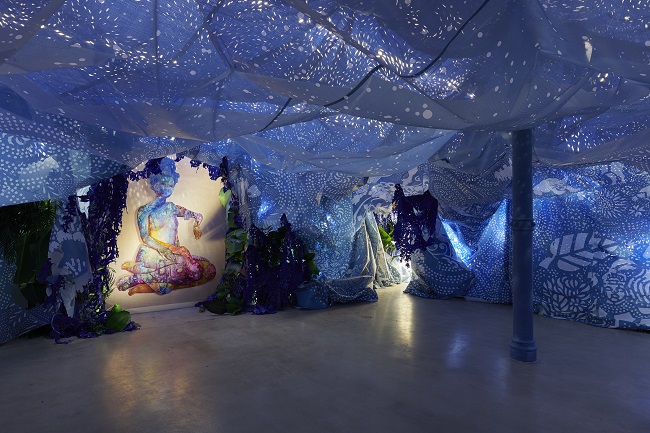 Firelei Báez, A Drexcyen chronocommons (To win the war you fought it sideways), 2019 (detail), two paintings, hand-painted wooden frame, perforated tarp, printed mesh, handmade paper over found objects, plants, books, Oman incense and palo santo, The Joyner/ Giuffrida Collection, Courtesy the Artist and Hauser & Wirth, New York, Photo: Phoebe d’Heurle, © Firelei Báez