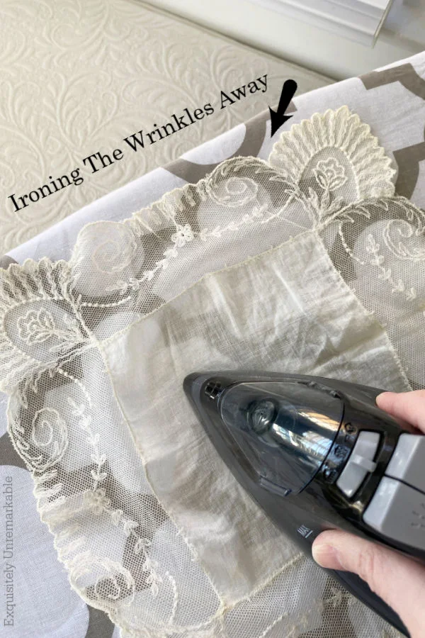 Ironing Lace handkerchief with a black iron on ironing board