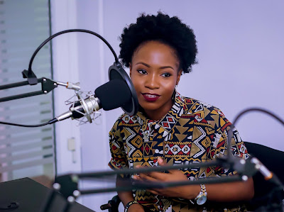 black woman speaking into a podcast mic attached to a mechanical arm.