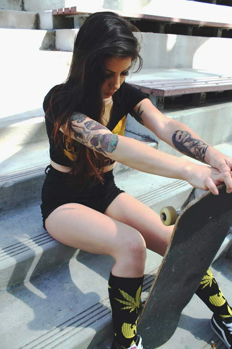 Foto de mujer con tatuajes y skateboard