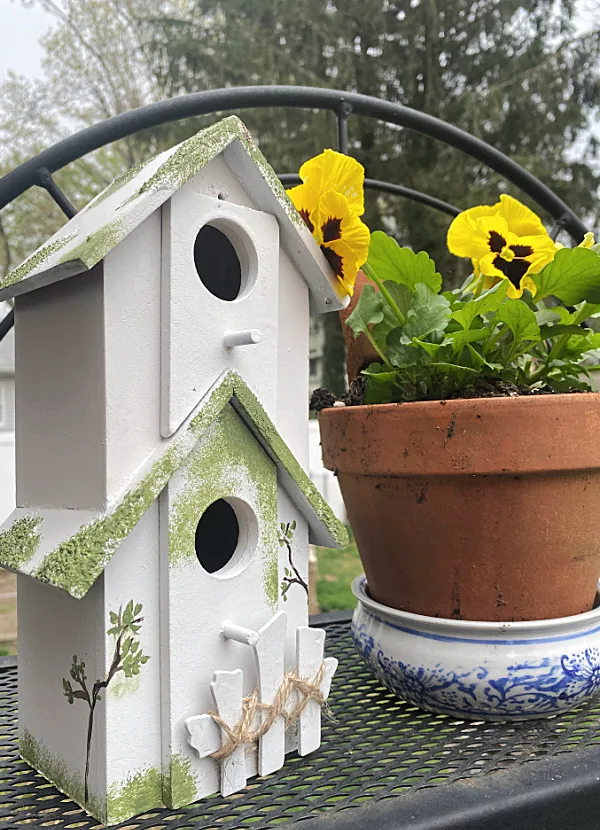 birdhouse and pot of pansies