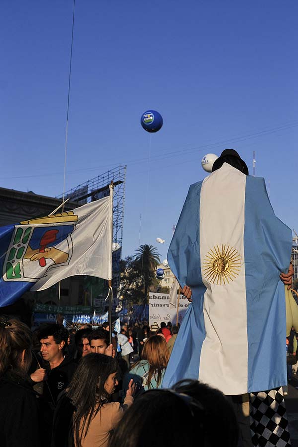 bandera de argentina y del partido justicialista en un acto en la calle con escenario de fondo