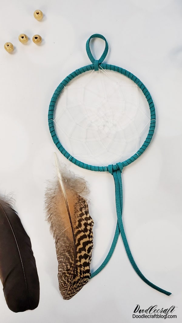 Use more of the cotton thread to tie some wooden beads onto the dreamcatcher.
