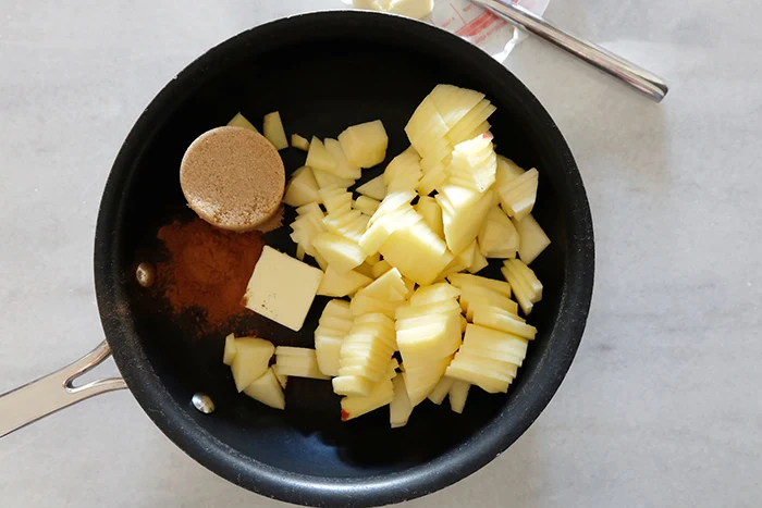 sliced apples in pan with brown sugar, butter, and spices