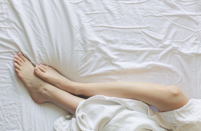 Woman's leg comfy on a mattress with white sheet