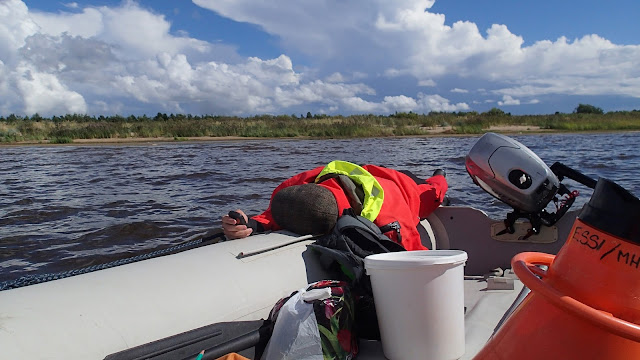 Pelastautumispukuinen henkilö retkottaa kumiveneen ponttoonilla