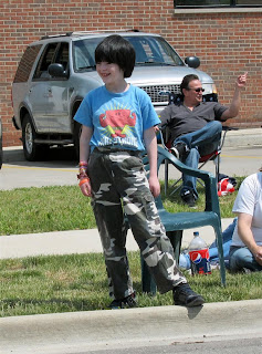 happy vampire, kid, super white, camo pants, by road at parade