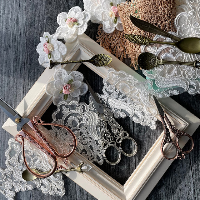 embroidery scissors, lace, teaspoons and a frame