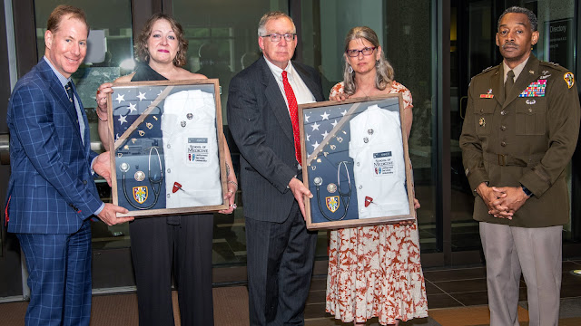 A group of people presenting framed uniforms