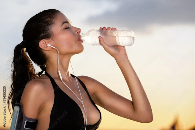 Woman drinking water outdoors at sunrise
